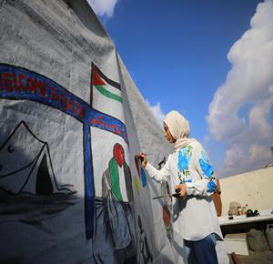 الطفلة النازحة سارة سعدة (14 عامًا) تمارس شغفها الفني بالرسم في خيمتها بمدينة غزة. وتحاول سارة التعبير عن معاناة أهالي قطاع غزة وإيصال صوتهم إلى العالم، من خلال لوحاتها الفنية.